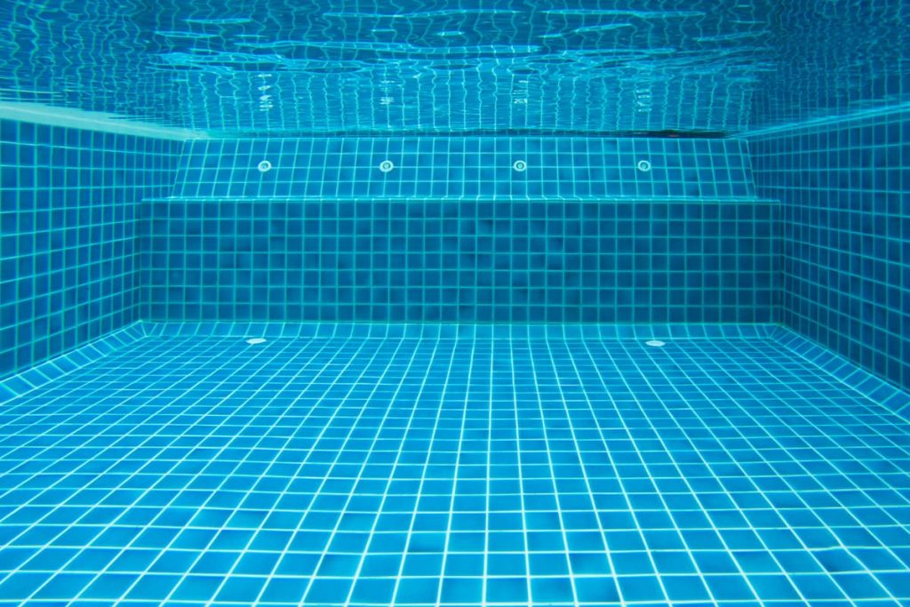 Piscina Cleaning.Net para limpiar la piscina en manos masculinas sobre fondo azul de agua. Filtración de agua con una red en la piscina. Herramienta de limpieza de la piscina Fotografía de stock